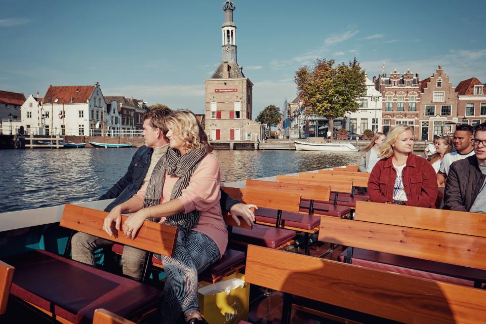 Mensen op houten bankjes op een rondvaart boot in Alkmaar