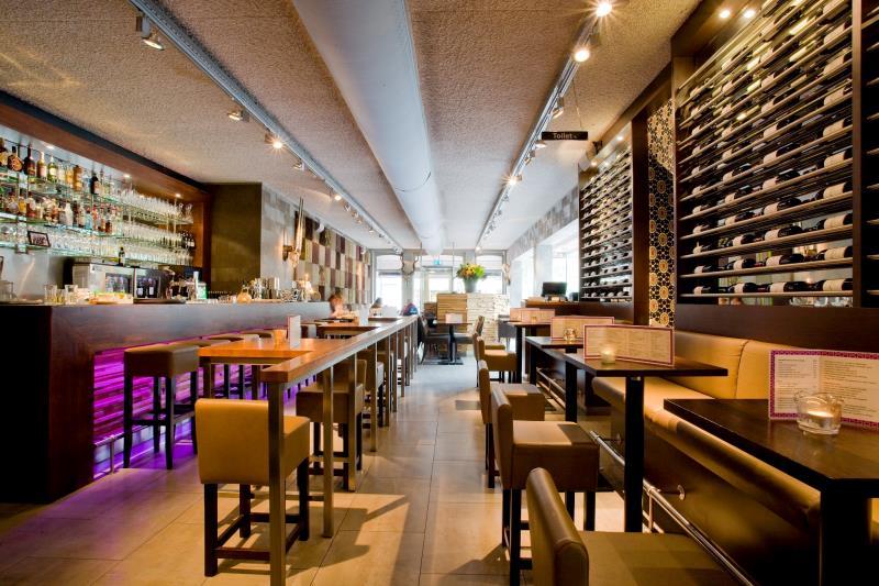 binnen bij abbys met een bank met tafels en links een bar