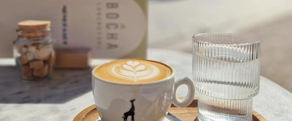Kopje koffie en glaasje water op de tafel bij Bocha