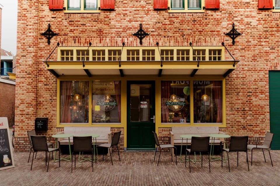 Vooraanzicht Alkmaars Koffiehuis met stoelen en tafels voor het gebouw