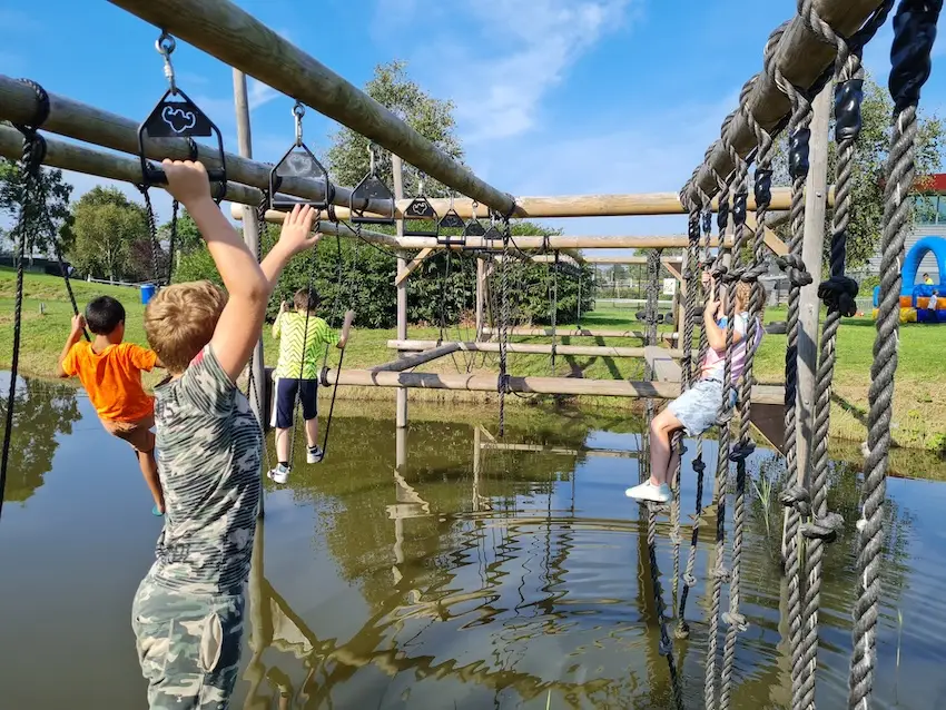 Kinderen op een houtenklimrek boven het water