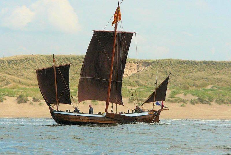houten boot op het water met op de achtergrond de duinen