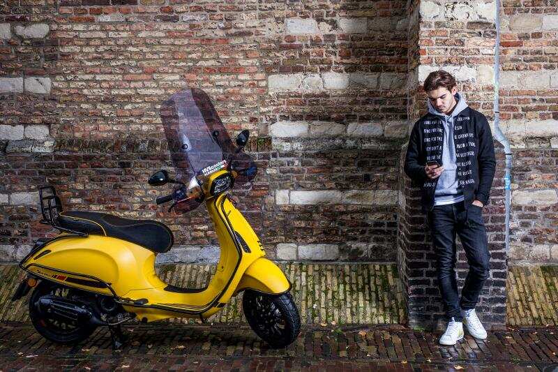 Gele scooter met een jongen er naast