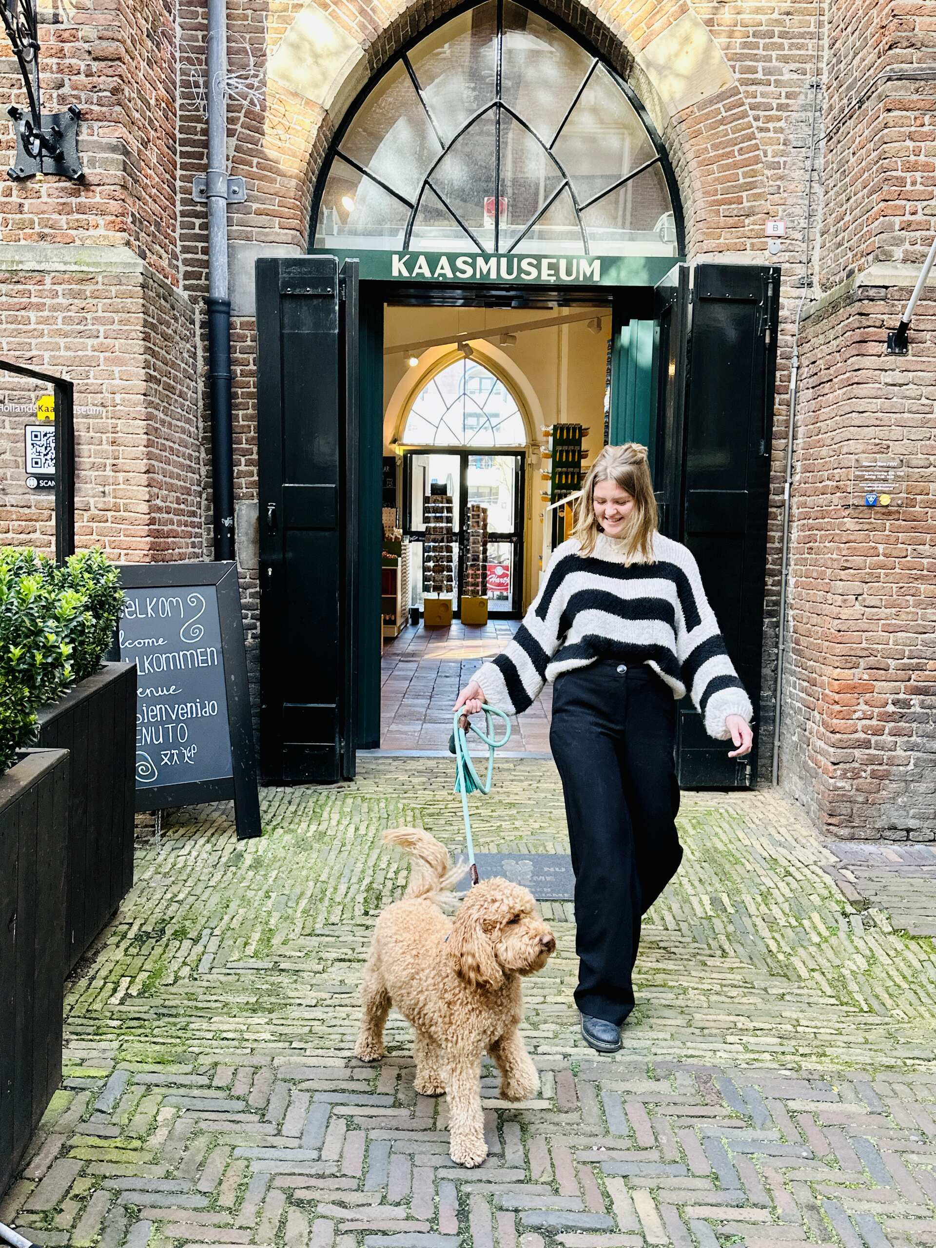 Vrouw laat hond uit bij het Kaasmuseum