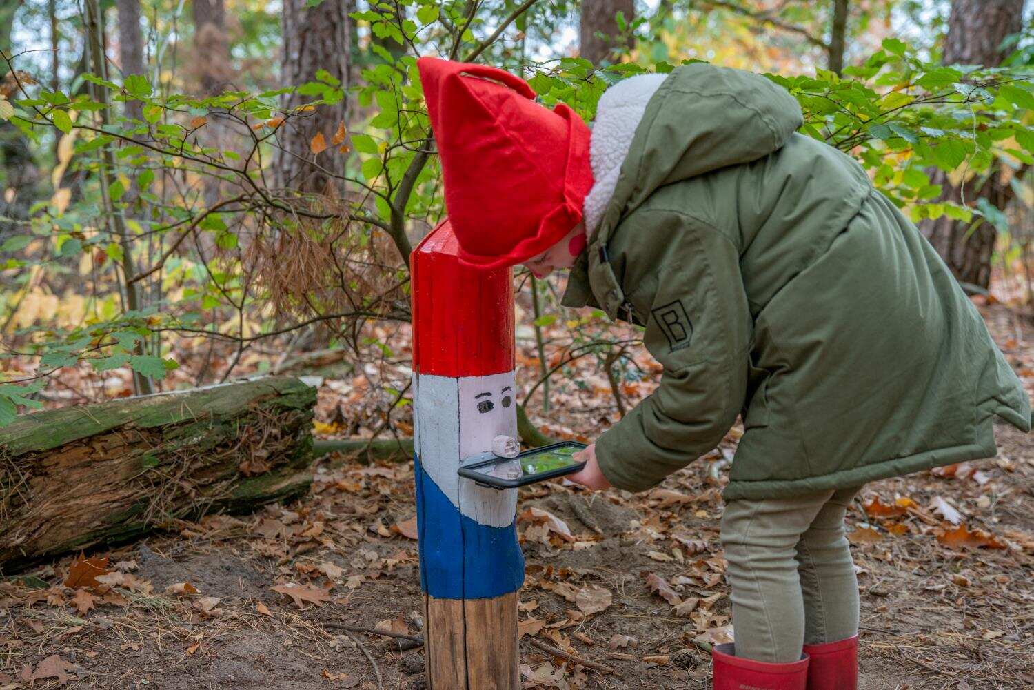 Kind staat bij een houten paal geschilderd als kabouter