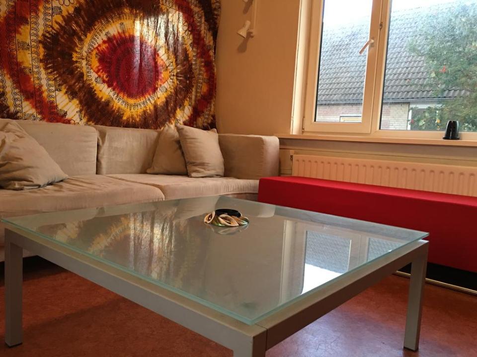 sfeervol appartement met een bruine bank een glazen tafel en een kleurrijke muur