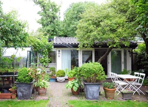 Huisje nassau met groene bomen en een kas ernaast